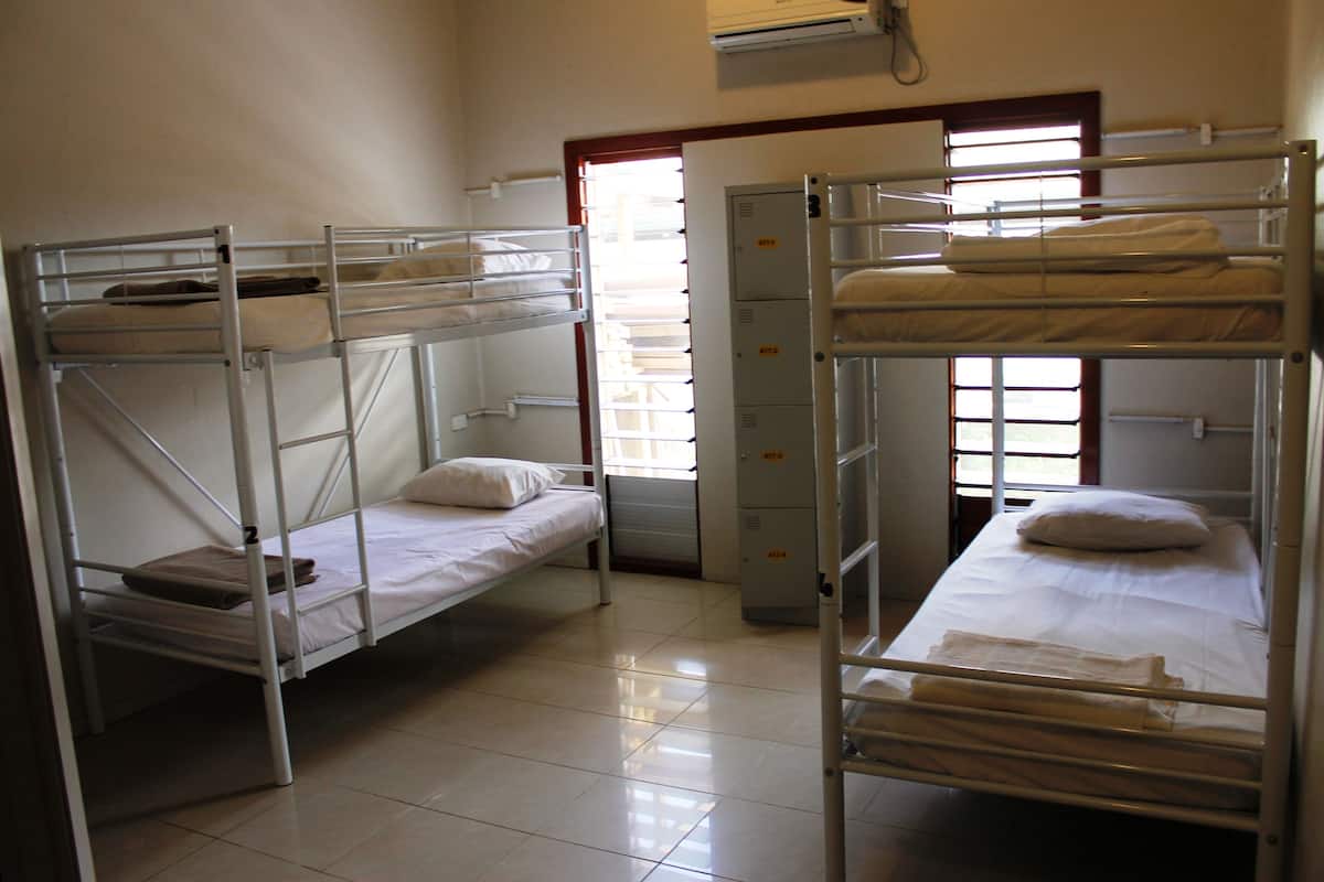 Habitación tipo dormitorio con literas, un armario y una ventana con persianas.