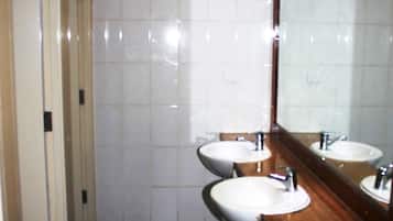 Un baño con dos lavamanos, un espejo y una pared con azulejos.