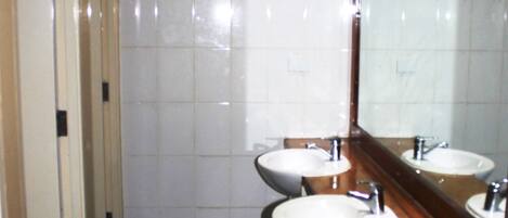 A bathroom with two sinks, a mirror, and a tiled wall.