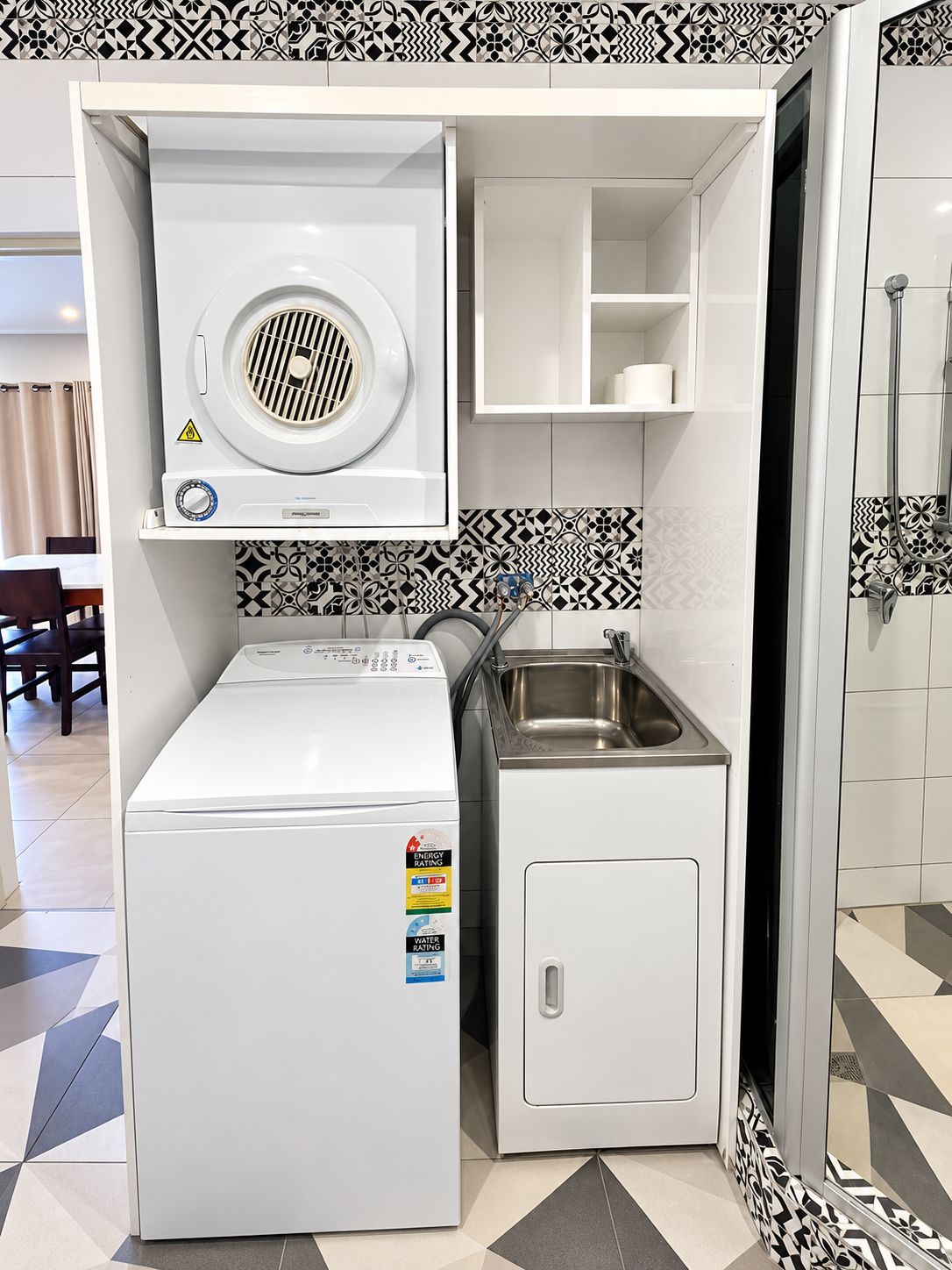 Een functionele wasruimte met een wasmachine en droger, een klein wasbakje en een kastje.