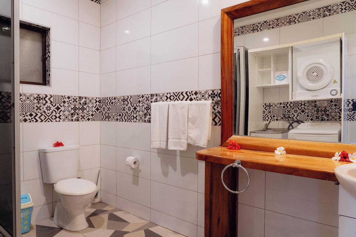 Een badkamer met toilet, wastafel en spiegel.