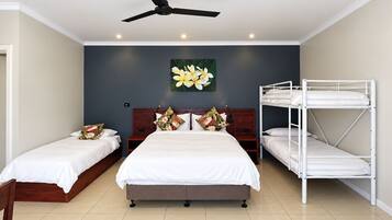 A hotel room with a large bed, two smaller beds, a ceiling fan, and a bunk bed.