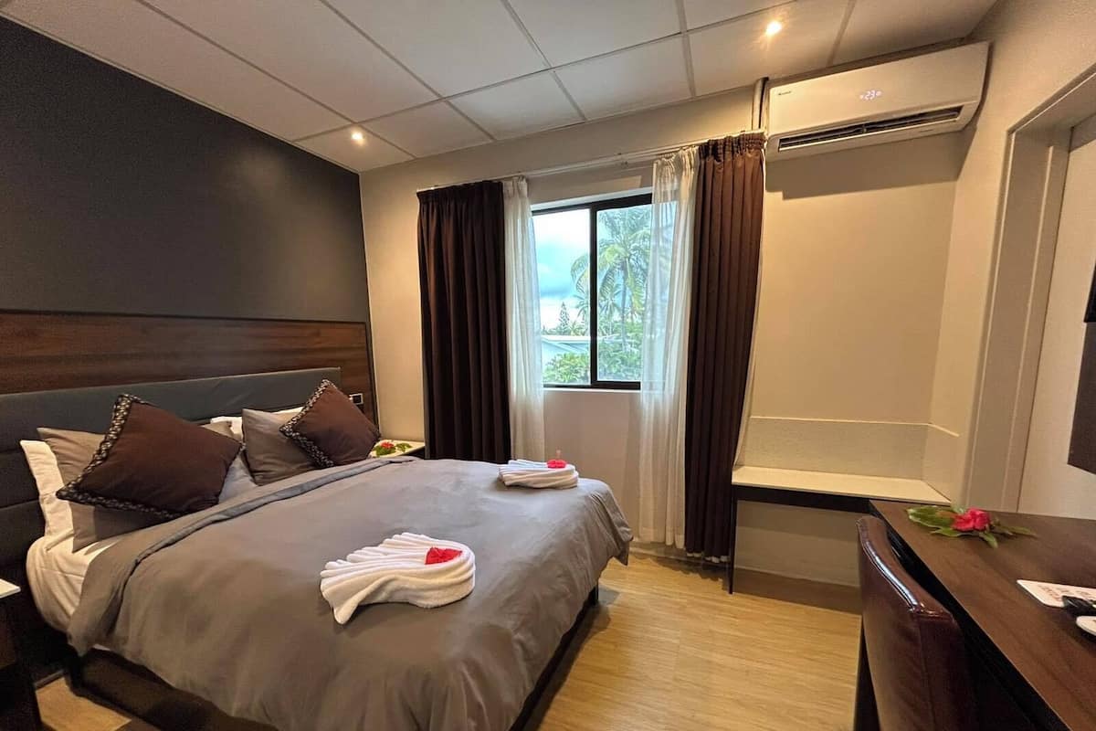 Una habitación de hotel con cama, mesita de noche y escritorio con silla.