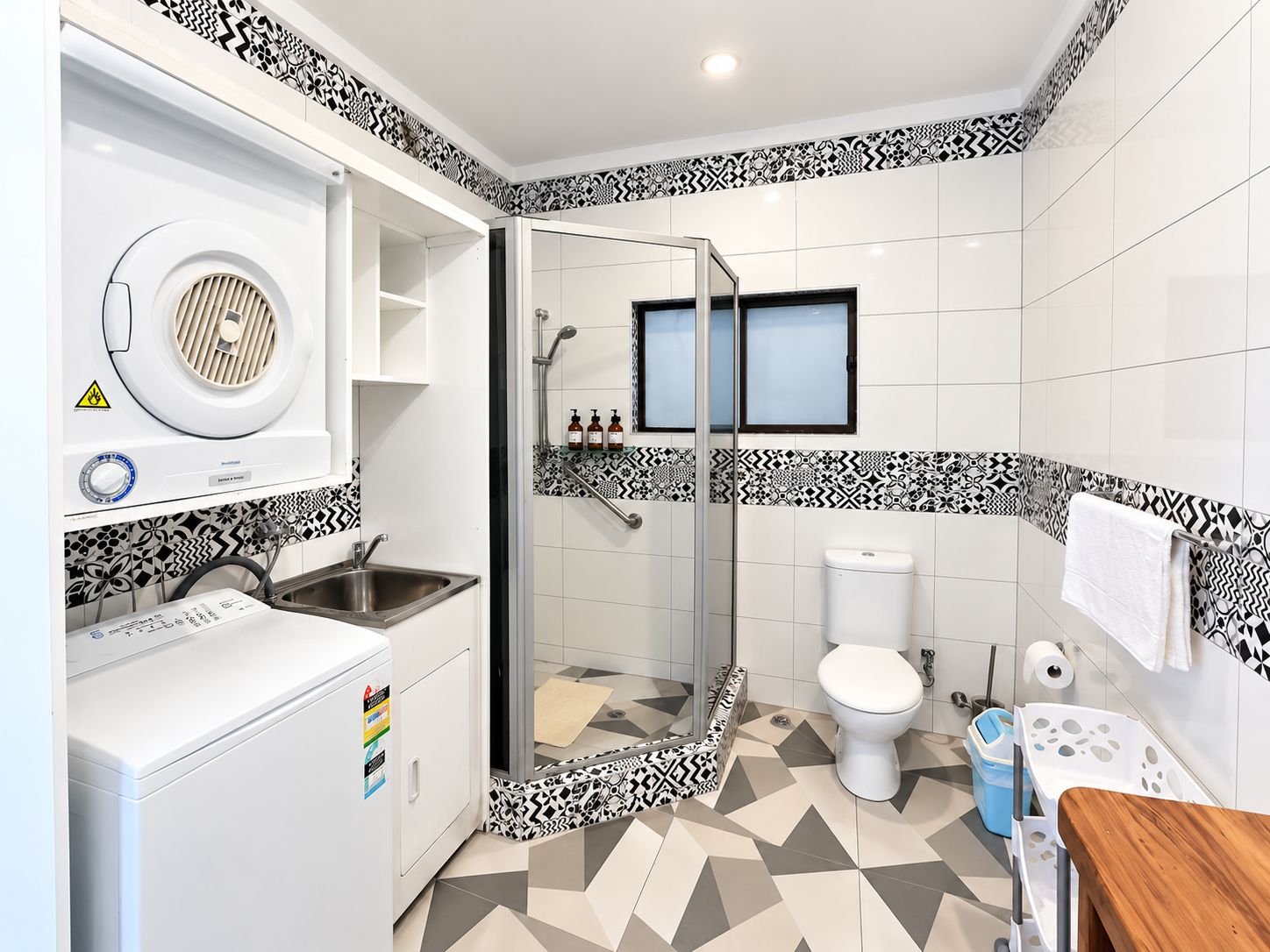 Un baño moderno con ducha, inodoro y lavadora integrada.