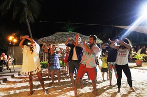 Un grupo de personas bailando sobre una playa arenosa de noche.
