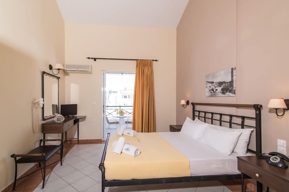 Een hotelkamer met een bed, nachtkastje, bureau, stoel en een raam met gordijnen.
