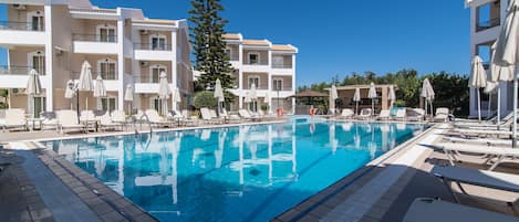 Una piscina al aire libre, sombrillas, tumbonas