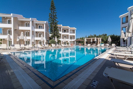 Una piscina al aire libre, sombrillas, sillones reclinables de piscina