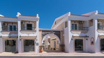 Un hotel con fachada moderna, varios balcones y una entrada despejada.
