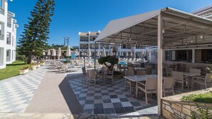 Une cour d’hôtel avec des espaces de détente en plein air, une piscine et un grand arbre.