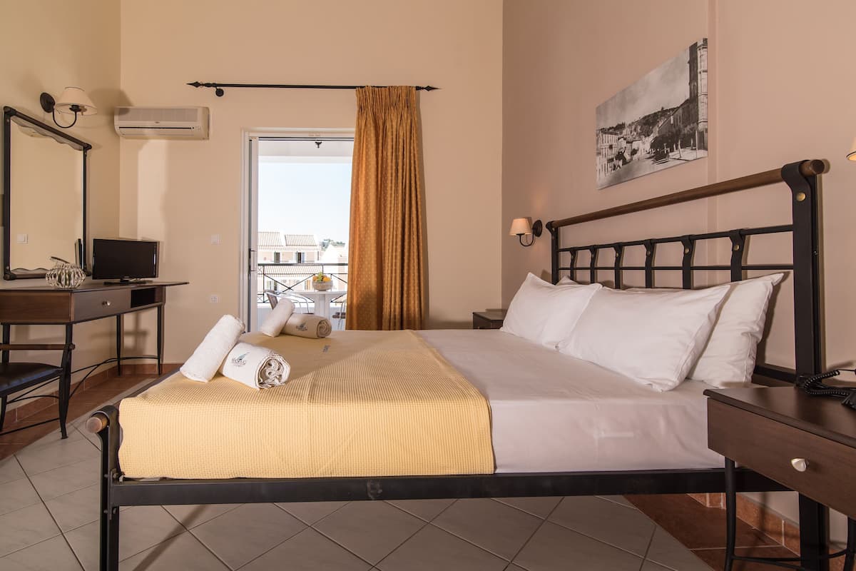 Hotelkamer met een bed, een bureau, een stoel, een televisie, een lamp, een schilderij en een raam met gordijnen.