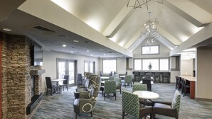 A spacious indoor area with a stone fireplace, multiple seating arrangements, and large windows allowing natural light. - Residence Inn by Marriott Dothan (Dothan)