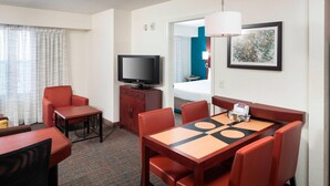 A hotel room with a TV, a dining table with chairs, a bed, and a bathroom visible through an open door. - Residence Inn by Marriott Dothan (Dothan)