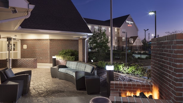 A hotel courtyard with outdoor seating, a brick fire pit, and a well-lit entrance. - Residence Inn by Marriott Dothan (Dothan)