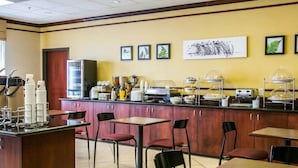 A breakfast area with a counter, coffee machines, and a variety of food items displayed. - Sleep Inn & Suites New Braunfels (New Braunfels)