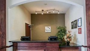 A reception desk with a sign reading "Sleep Inn & Suites" and a reception area with a wooden counter and a plant. - Sleep Inn & Suites New Braunfels (New Braunfels)