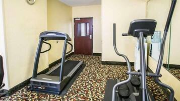 A hallway with a treadmill, a stationary bike, and a patterned carpet.
