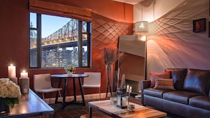 A modern living room with a city view, a fireplace, a sofa, and a dining area with candles.