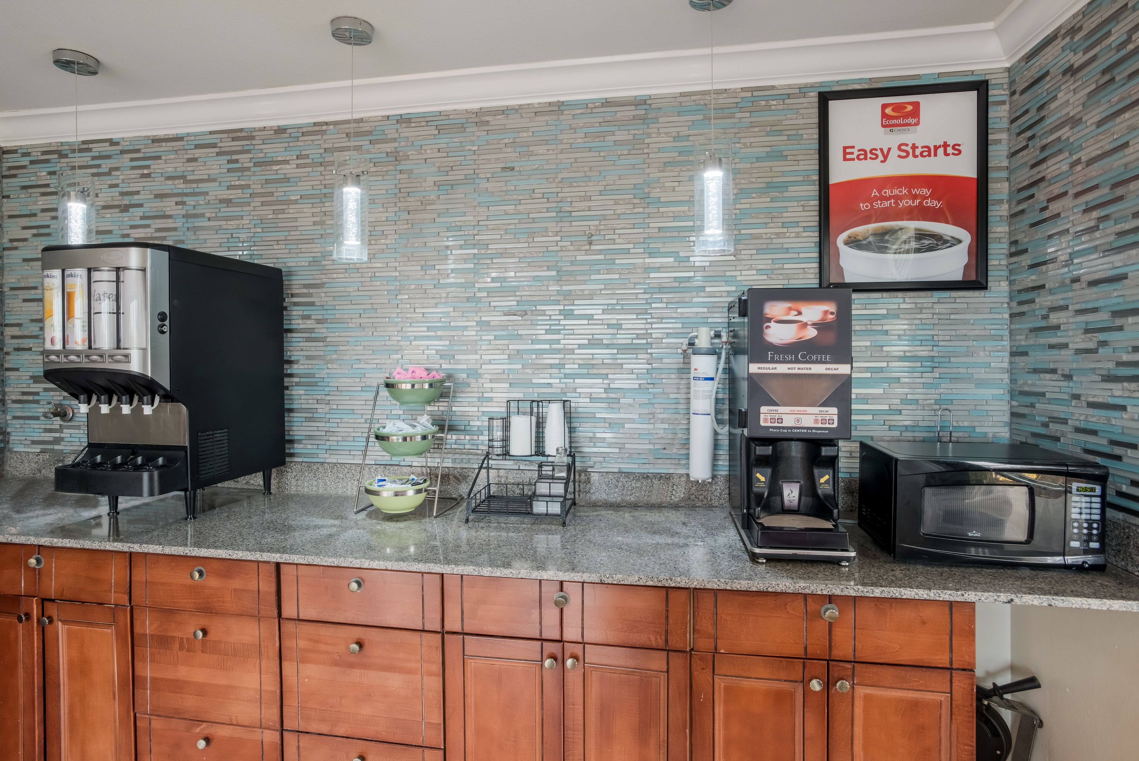 A kitchen area with a coffee machine, a microwave, and a coffee dispenser.