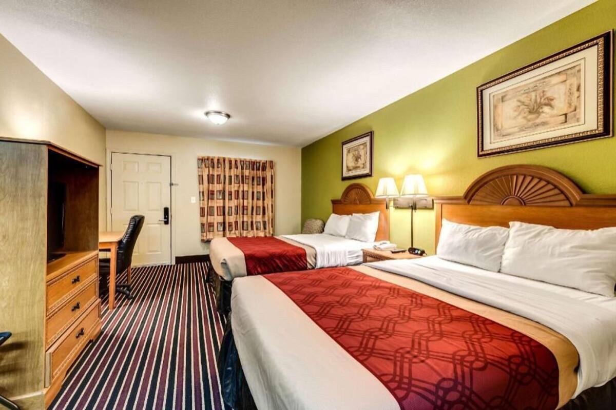 Een hotelkamer met twee bedden, een bureau, een stoel, een televisie en een kledingkast.