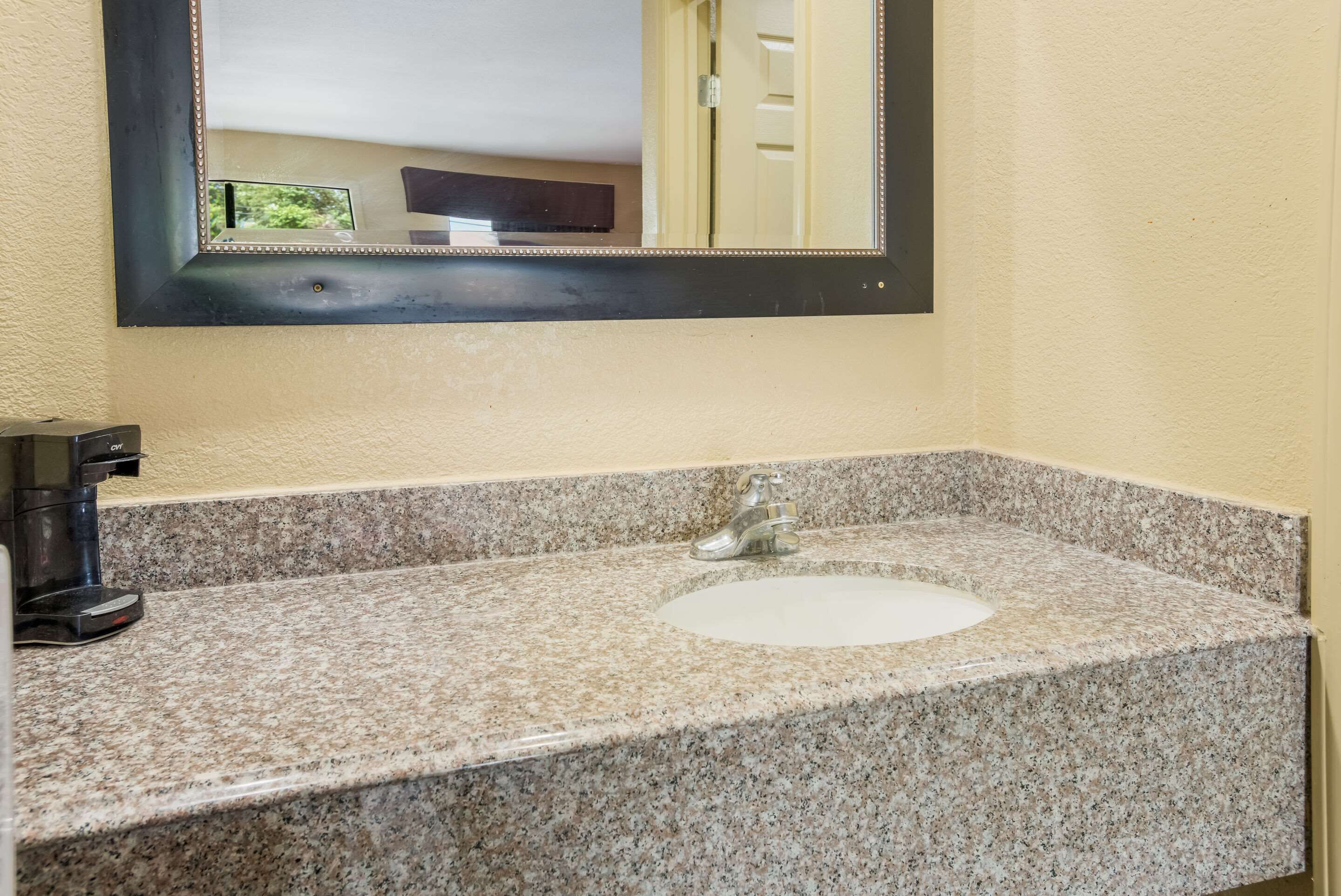 A bathroom with a granite countertop, a sink, and a mirror above it.