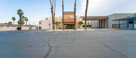 A Royal Plaza Inn with a parking lot, palm trees, and a building with a tiled facade.