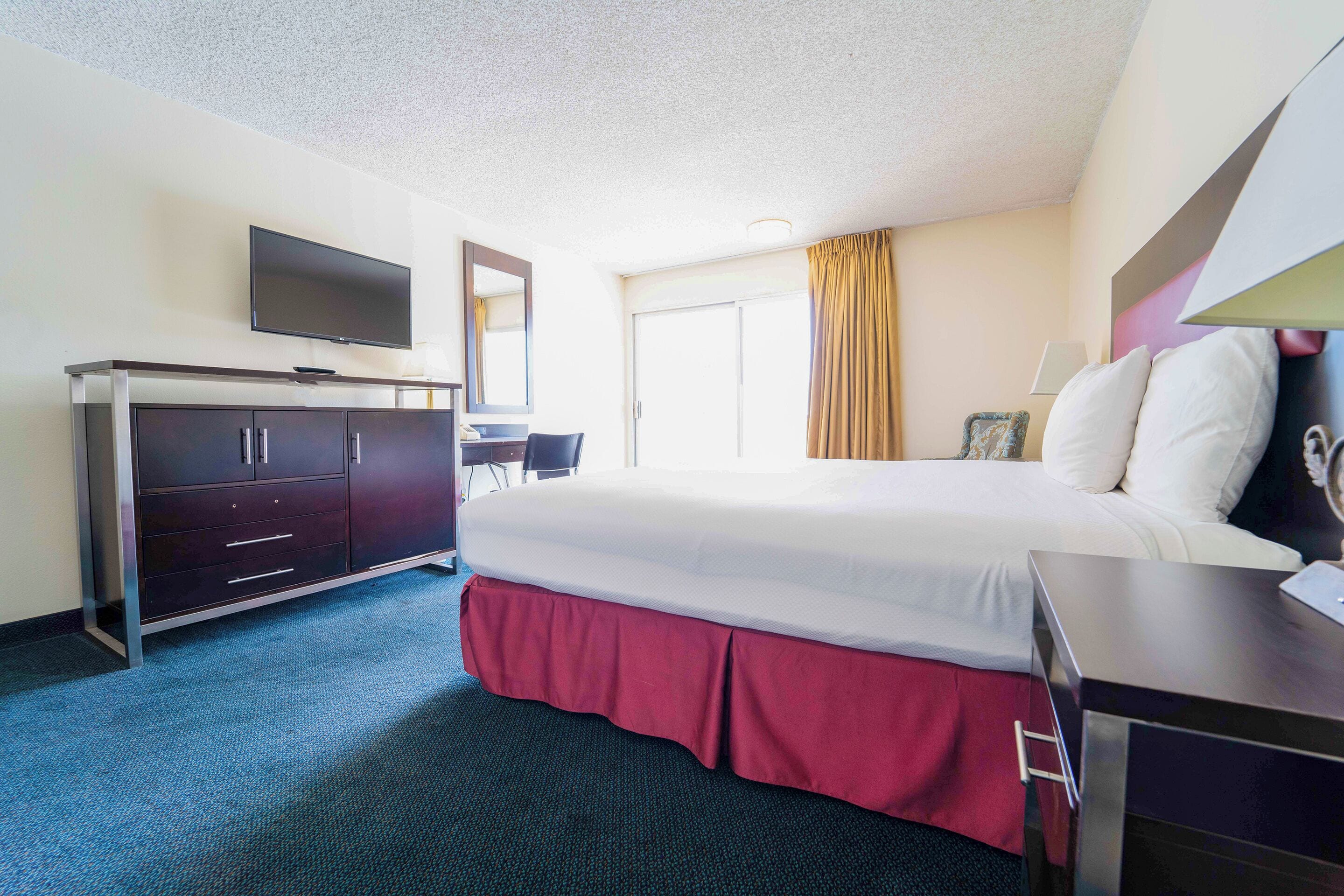 A hotel room with a bed, a desk, a television, and a wardrobe.