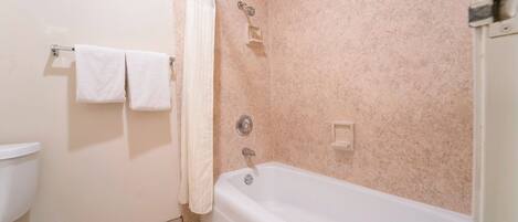 A bathroom with a bathtub, a toilet, and a towel rack.