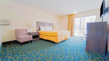 Ein Hotelzimmer mit Bett, Schreibtisch, Stuhl, Fernseher und Blick ins Freie.