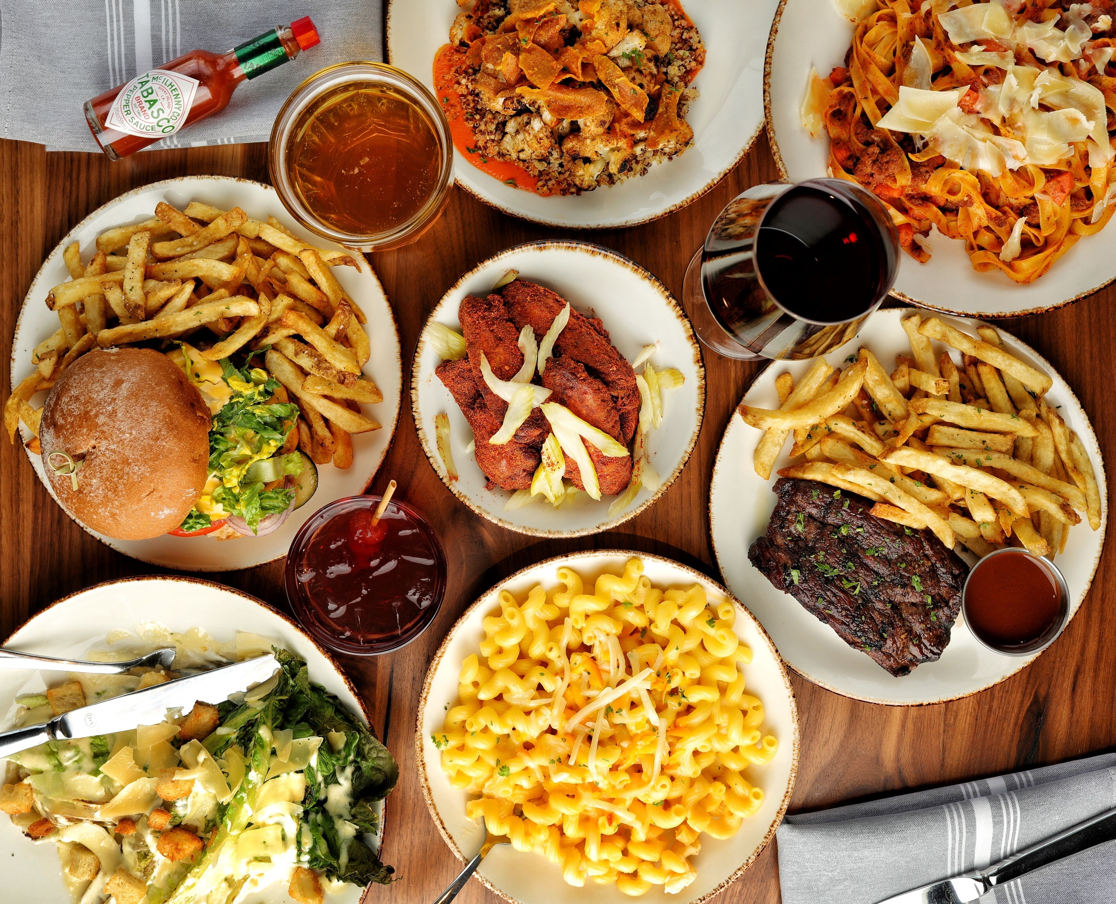 Diverse gerechten, waaronder een hamburger, frietjes, macaroni, salade en steak, wat doet denken aan een restaurant.