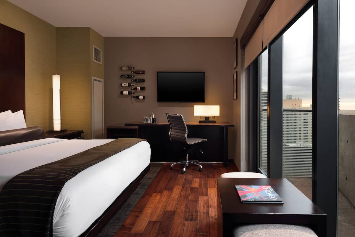 Une chambre d’hôtel avec un grand lit, un bureau avec une chaise, une télévision et une vue sur la ville.