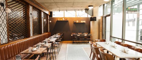 A restaurant with wooden booths and tables, a patterned floor, and large windows.