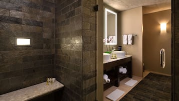 Ein modernes Badezimmer mit Steinwand, Waschtisch mit Spiegel und Duschbereich.