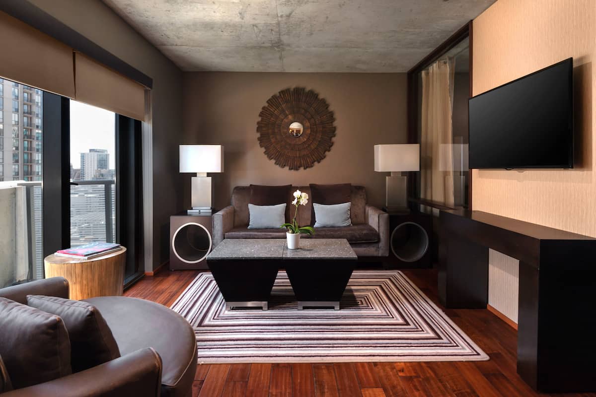 Un salon moderne comprenant un canapé, une table basse et deux petites tables d’appoint, une grande horloge murale et un téléviseur à écran plat fixé au mur.