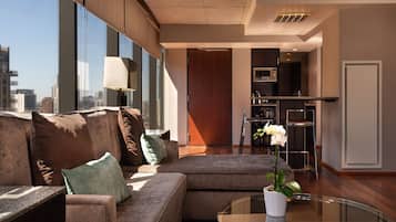 A modern living room with a sectional sofa, a glass coffee table, and a view of the city through large windows.