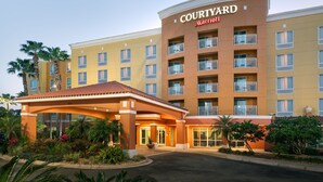 Een Courtyard Marriott hotel met een centrale ingang, meerdere balkons en een aangelegde tuin met palmbomen.