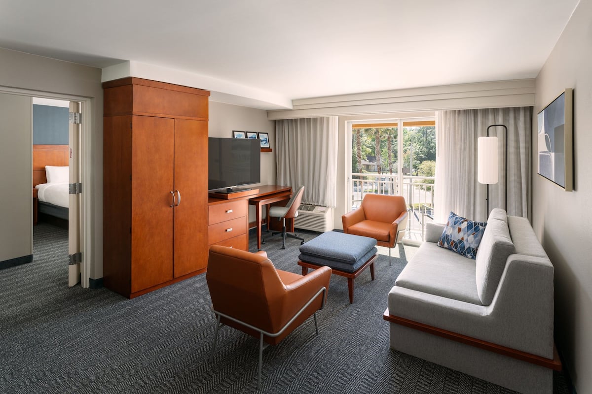 Habitación de hotel con cama, escritorio, televisor, sofá y una silla.