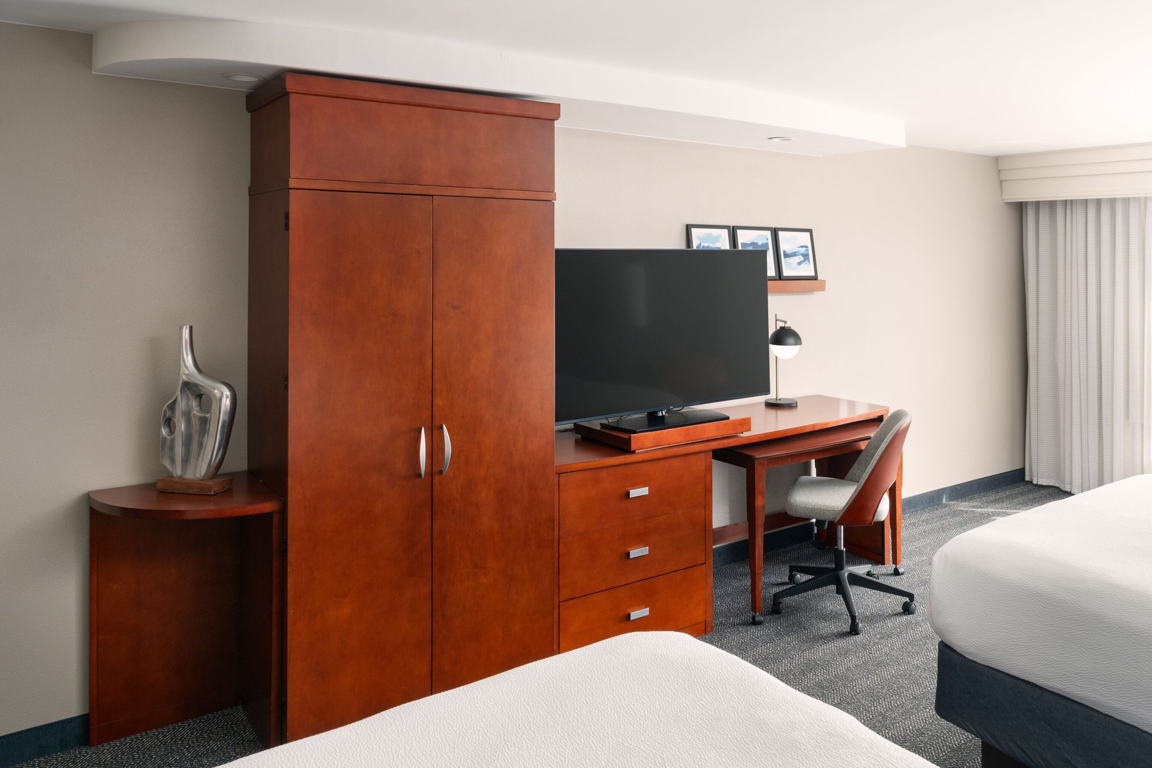 Ein Hotelzimmer mit einem Holztisch, einem Fernseher, einem Bett und einem Sessel.
