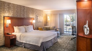 Een hotelkamer met een groot bed, een bureau, een stoel en uitzicht op de omgeving.