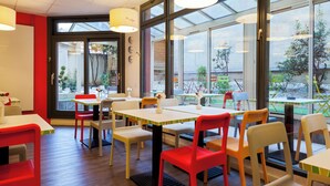 Un comedor interior bien iluminado con mesas y sillas, ventanas amplias y vistas al exterior.