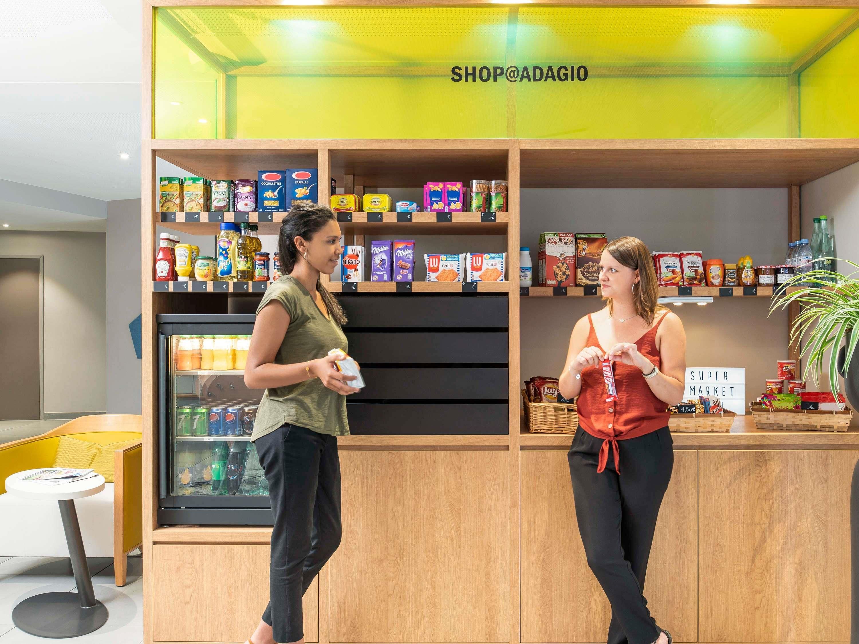 Una tienda minorista moderna con estanterías de madera llenas de diversos productos alimenticios, un mostrador refrigerado y un letrero que indica 'Super Market'.