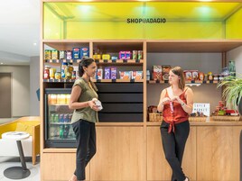 Una tienda minorista moderna con estanterías de madera llenas de diversos productos alimenticios, un mostrador refrigerado y un letrero que indica 'Super Market'.