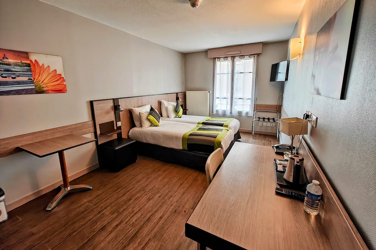 A hotel room with a bed, desk, chair, and a TV on the wall.