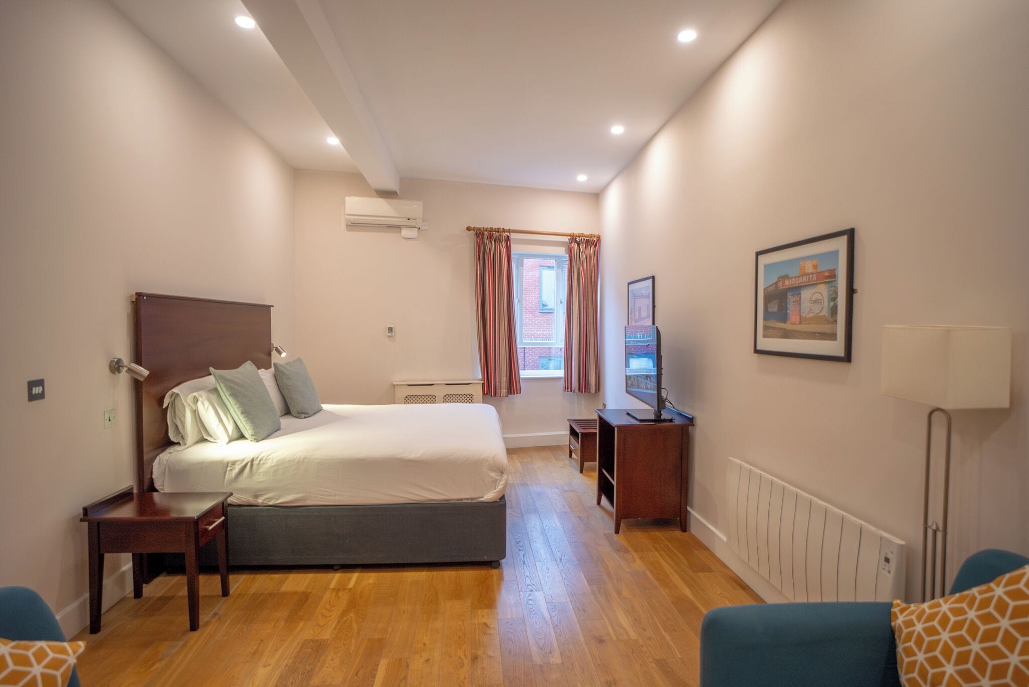 A bedroom with a bed, bedside table, lamp, and a TV.