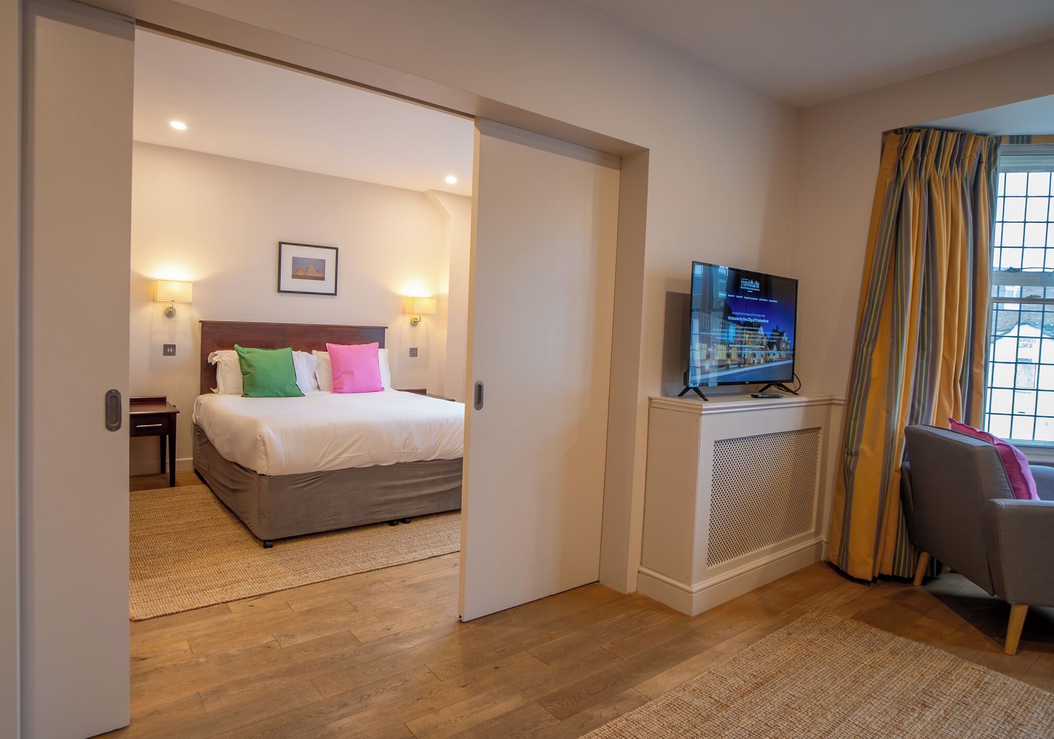 A hotel room with a bed, a television, a desk, and a chair.