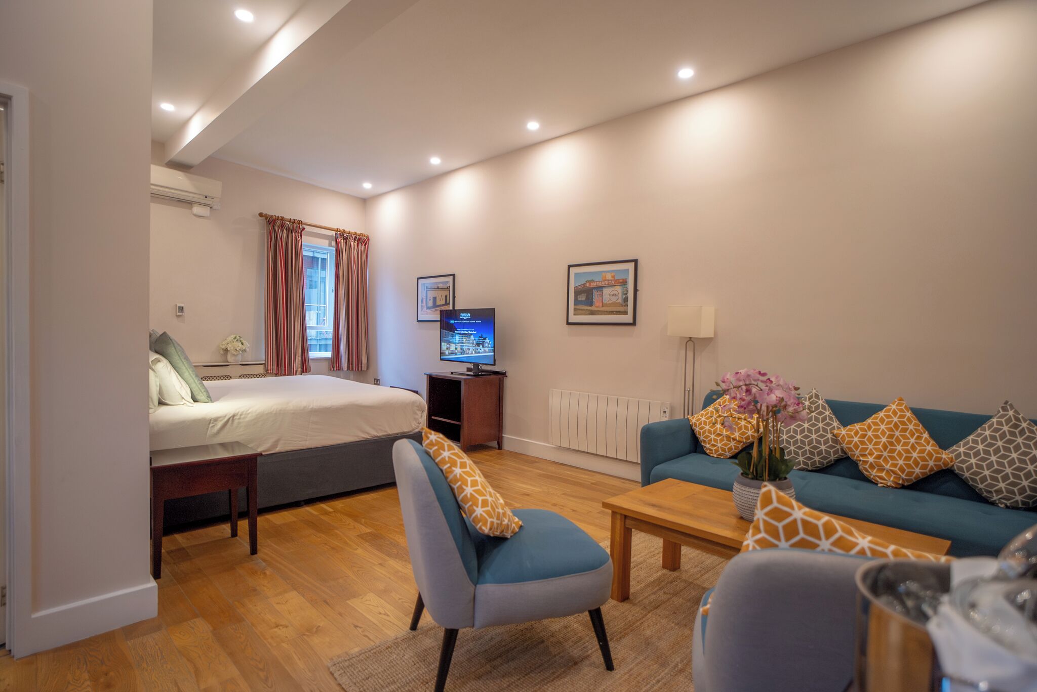 A modern hotel room with a bed, a TV, a sofa, and a coffee table.
