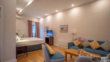 A modern hotel room with a bed, a TV, a sofa, and a coffee table.