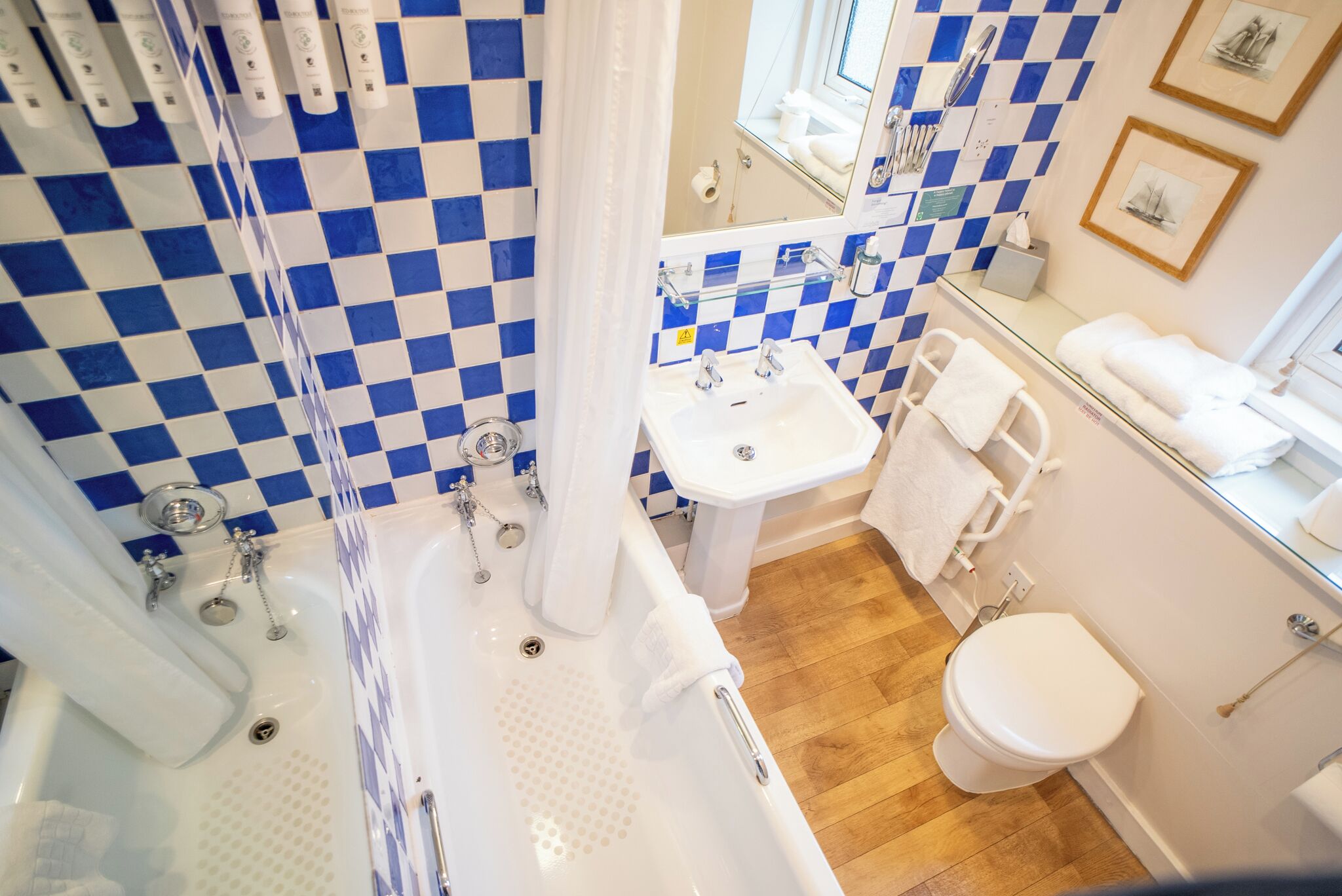 A bathroom with a checkered blue and white tile wall, a white sink, a bathtub, and a toilet.