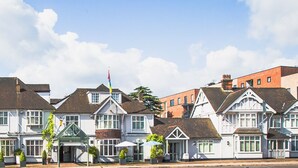 A row of traditional white buildings with gabled roofs, a flag, and outdoor seating areas. - County Hotel Chelmsford (Chelmsford)