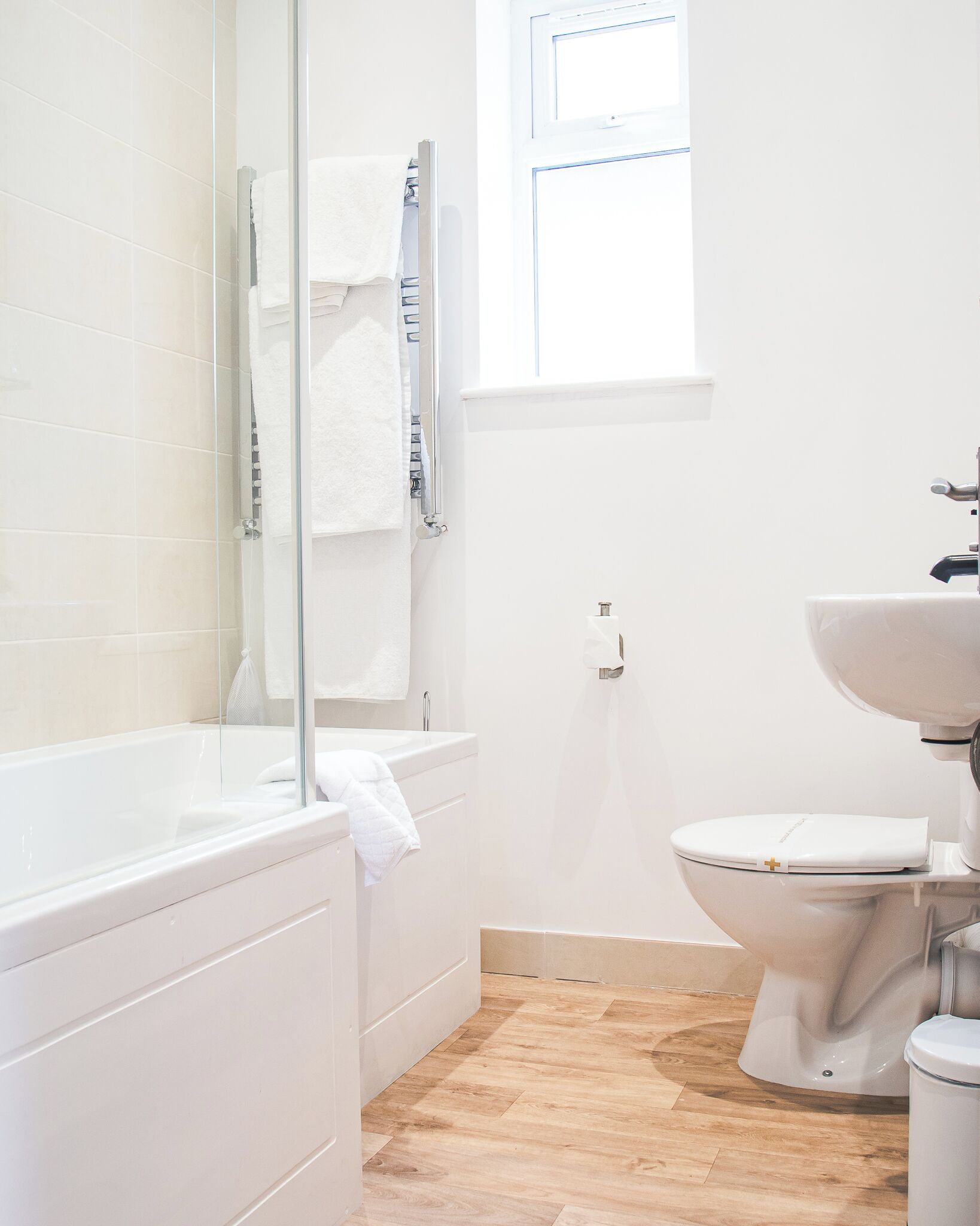 Un baño moderno con bañera, inodoro y ventana que proporciona luz natural.